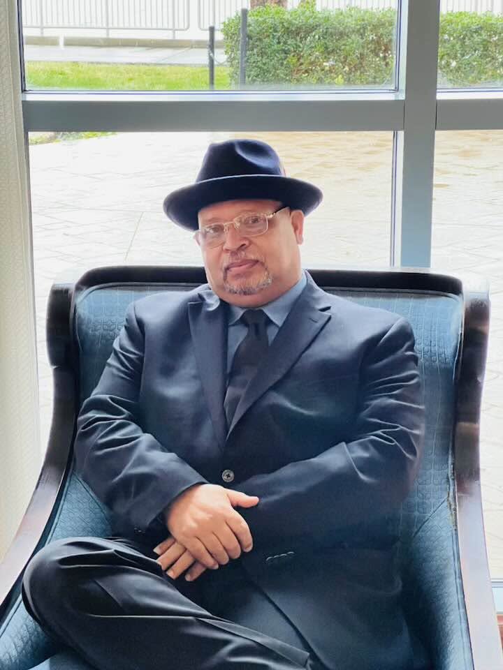 Portrait of Earl Owens III in a suit and hat