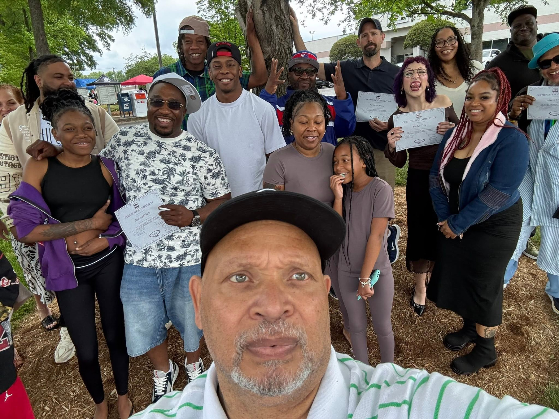 Earl Owens III with graduates holding their certificates outdoors